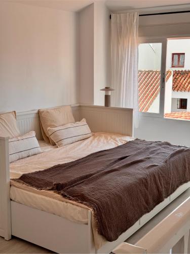 a large bed in a white room with a window at Casa Feliz in Torrox Costa
