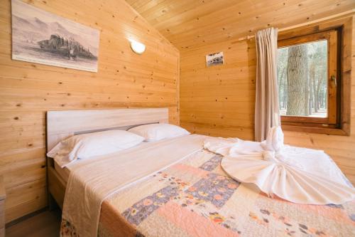 a bedroom with a bed in a log cabin at Safari Beach & Camping in Donji Štoj