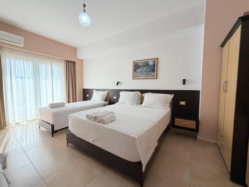 a bedroom with two beds and a large window at Aparthotel PAJA Ksamil in Ksamil