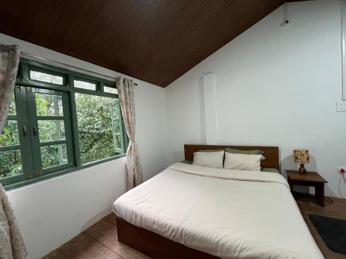 a bedroom with a bed and two windows at Chara Farmhouse in Kohīma