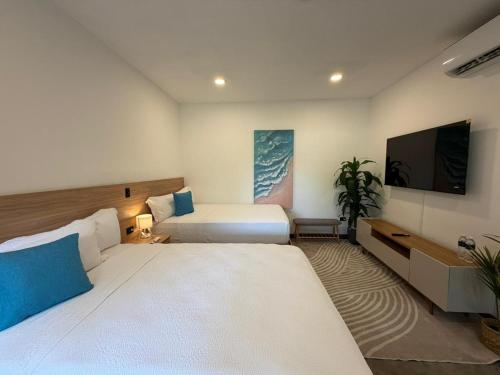 a hotel room with two beds and a flat screen tv at Cardedeu Residence Cangrejera in La Libertad