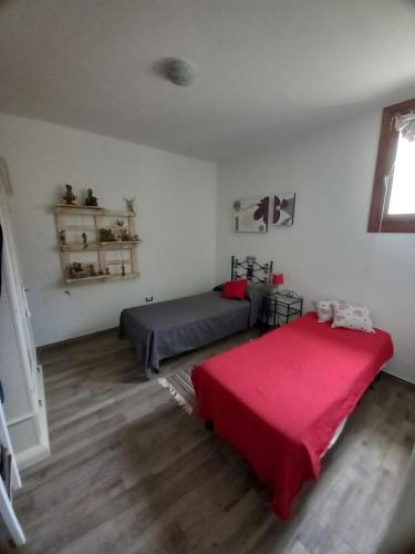 a bedroom with two beds and a red blanket at Casa Orchidea in Aggius