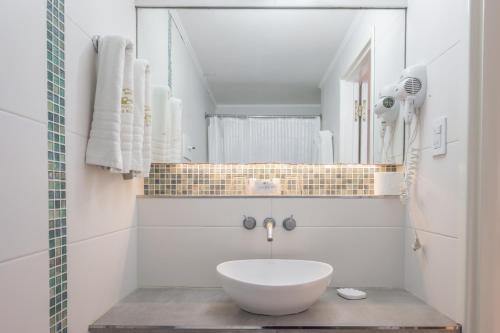 ein Badezimmer mit einem weißen Waschbecken und einem Spiegel in der Unterkunft Hotel Las Rocas in Mar del Plata