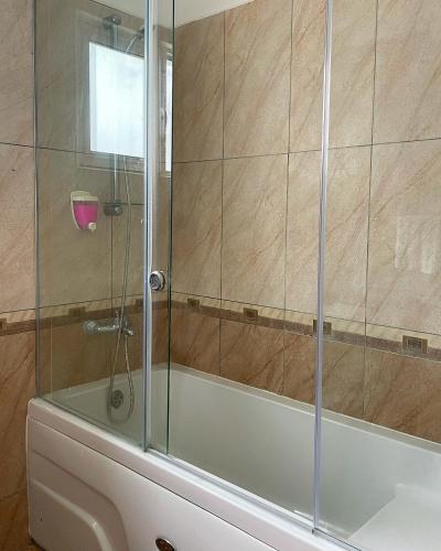 a shower with a glass door next to a tub at RiX Sunny Apartments in Kyrenia