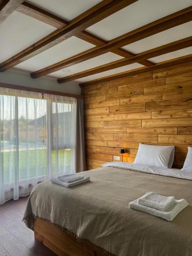 a bedroom with a large bed and a large window at Братановите Къщи in Dŭbravka