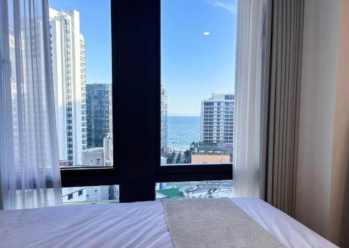a bedroom with a view of the ocean from a window at Stay in MooD in Busan