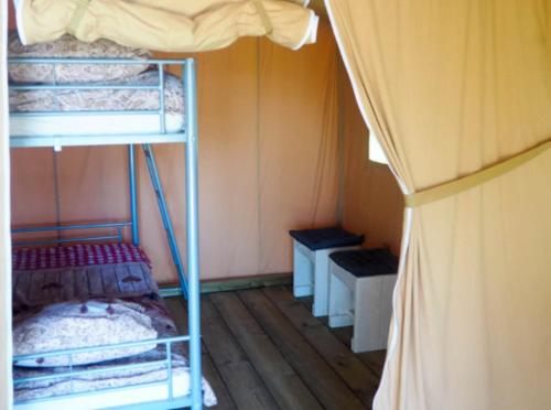 a room with three bunk beds in a room at Ingerichte safaritent in Saint-Priest-en-Murat