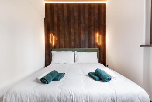 a white bed with two green pillows on it at Cozy Loft near MXP AIRPORT & RHO FIERA - 4 GUESTS - Parking FREE in Legnano