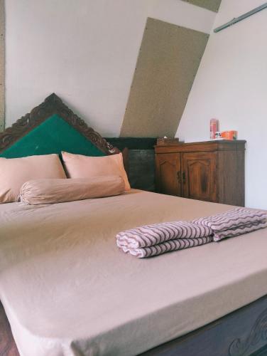 a bedroom with a bed with a wooden headboard at Zalfa Homestay in Taliwang