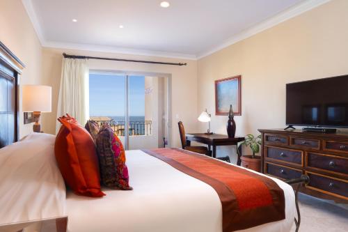 a bedroom with a bed with a television and a desk at Villa la Estancia Beach Resort & Spa in Cabo San Lucas