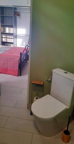 a bathroom with a toilet in a room with a bed at Cocon Kréyòl in Sainte-Anne