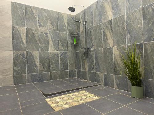 a bathroom with a shower and a tile wall at GRAND Restaurant&Hotel in Daugavpils