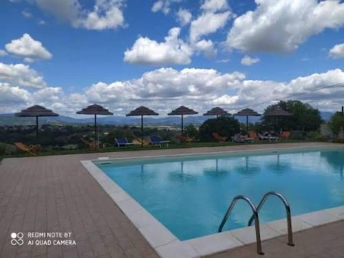 a large swimming pool with umbrellas on a patio at La Casa di Nonna Iolanda in Gualdo Cattaneo