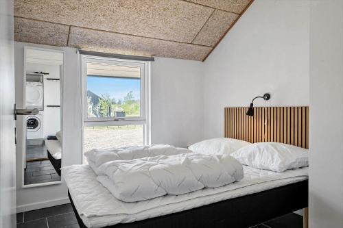 a bedroom with a bed with white sheets and a window at JB500-Brovst-Kronvildtvej-31 in Tranum Strand
