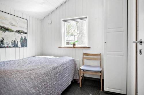 a bedroom with a bed and a chair and a window at 30717-Odder-Alrovej-153 in Amstrup