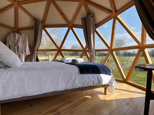 a bed in a room with a large window at Dôme géodésique - Baie de Somme in Favières