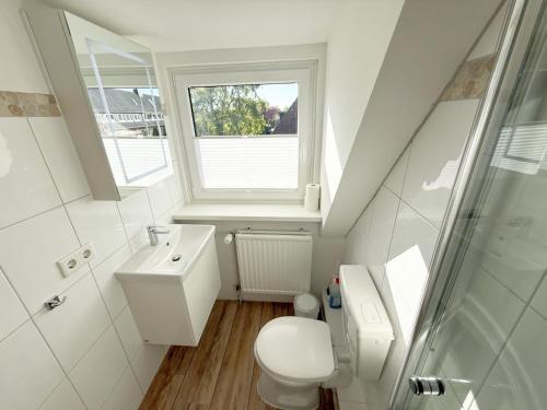 a bathroom with a toilet and a sink and a window at Westerheide 51, App 2 in Wenningstedt