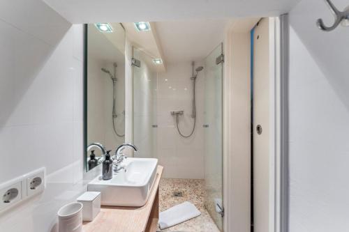 a white bathroom with a sink and a shower at Friesenhaus Hideaway Hüs in Morsum