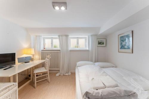 a white bedroom with a bed and a desk at Friesenhaus Hideaway Hüs in Morsum