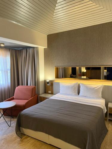 a bedroom with a large bed and a red chair at The Alaçatı Ariel Hotel in Çeşme
