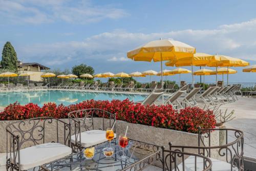 a pool with tables and chairs and umbrellas at Residence Borgo Dei Limoni - Appartamenti con Garage in Gargnano
