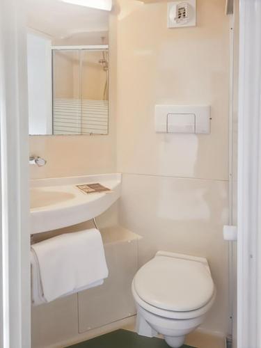 a white bathroom with a toilet and a sink at Good Night Hotel in Arques