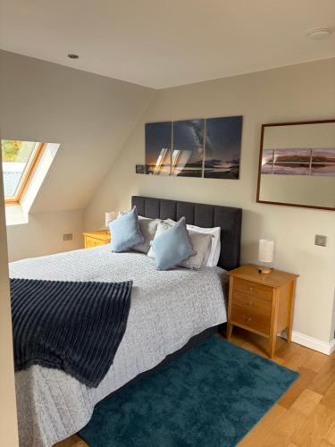 a bedroom with a large bed with blue pillows at Rockpool Apartment in Acharacle