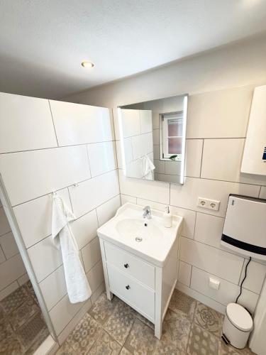 a white bathroom with a sink and a mirror at Fischerhus in Fehmarn