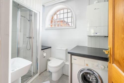 a white bathroom with a toilet and a sink at Ballygate Stable in Beccles