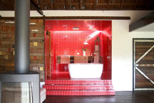 Habitación con baño rojo con bañera blanca. en BIG.SHED.HOUSE, en Huonville