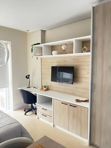 a room with a desk with a tv and a computer at 809 - Studio Moderno no Centro-Batel in Curitiba