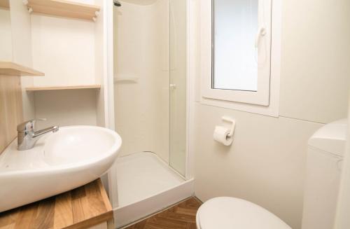 a white bathroom with a sink and a toilet at Safari Beach & Camping in Donji Štoj