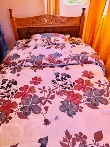 a bed with a floral bedspread on it at Enchanting Oasis in Embu