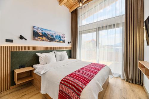 a bedroom with a large bed and a large window at Selva Cabins in Zărneşti