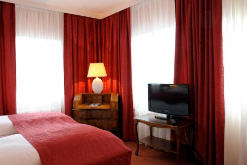 Habitación de hotel con cama y TV en Hotel Vier Jahreszeiten Salzburg, en Salzburgo