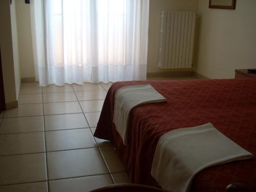 a bedroom with a bed and a window with curtains at Hotel Margherita in San Giovanni Rotondo
