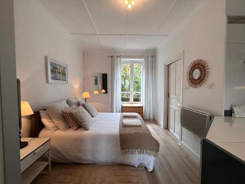 a white bedroom with a bed and a window at St Guenole' Studio Apartment in Landévennec