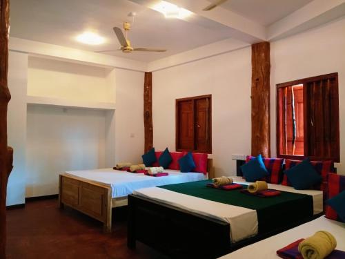a bedroom with two beds with blue and red pillows at Nature Beach Huts in Trincomalee