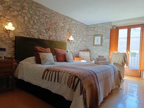 a bedroom with a large bed with a stone wall at Cal Blasi in Montblanc