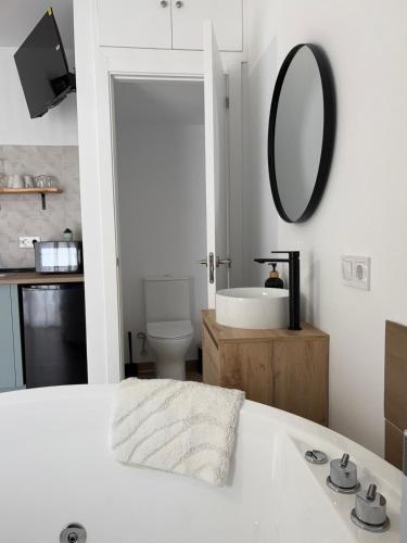 a white bathroom with a sink and a mirror at Loft Jacuzzi Algarrobo in Arcos de la Frontera