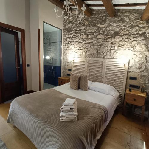 a bedroom with a large bed with a stone wall at Cal Blasi in Montblanc