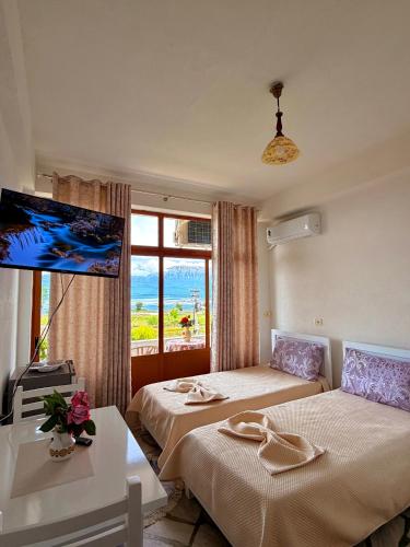 a hotel room with two beds and a tv at Mert Jacellari Guesthouse in Pogradec