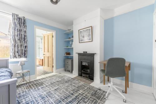 a bedroom with blue walls and a desk and a fireplace at Twin Tides in Hythe