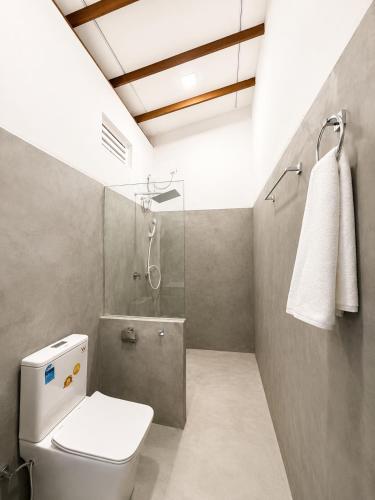 a bathroom with a white toilet and a shower at Jesoloresort Arugambay in Arugam Bay