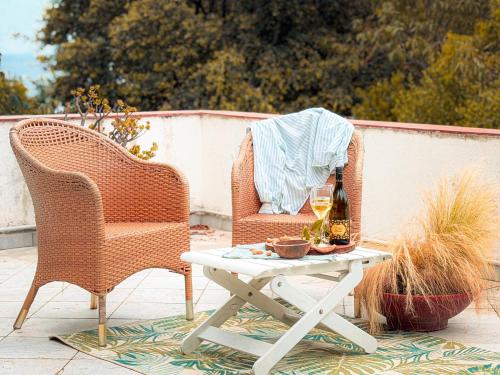 two wicker chairs and a table with a bottle of wine at Fuga d'Amore - HelloElba in Portoferraio