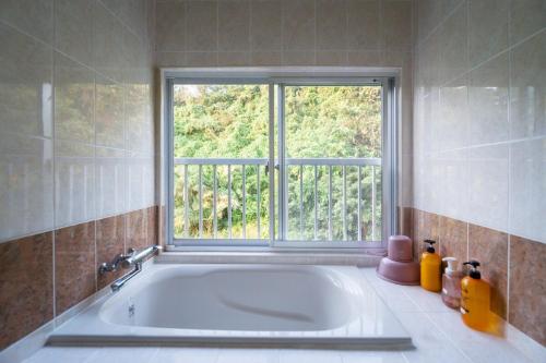 a bath tub in a bathroom with a window at Green Ocean Kingdom House in Uruma