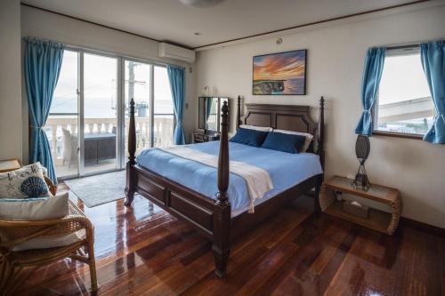 a bedroom with a bed with blue sheets and blue curtains at Green Ocean Kingdom House in Uruma
