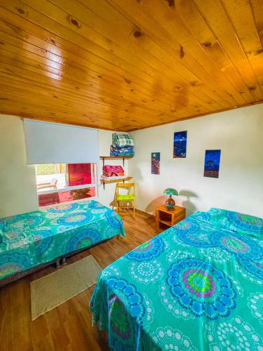 a bedroom with two beds and a wooden ceiling at Alojamiento EL GITANO in Filandia