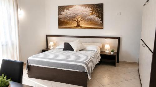 a bedroom with a bed with a tree painting on the wall at Domo - Guest-House Il Nespolo Fiorito in Orosei