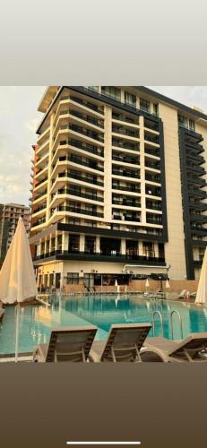 a hotel with a swimming pool and chairs in front of a building at Green side in Kvariati